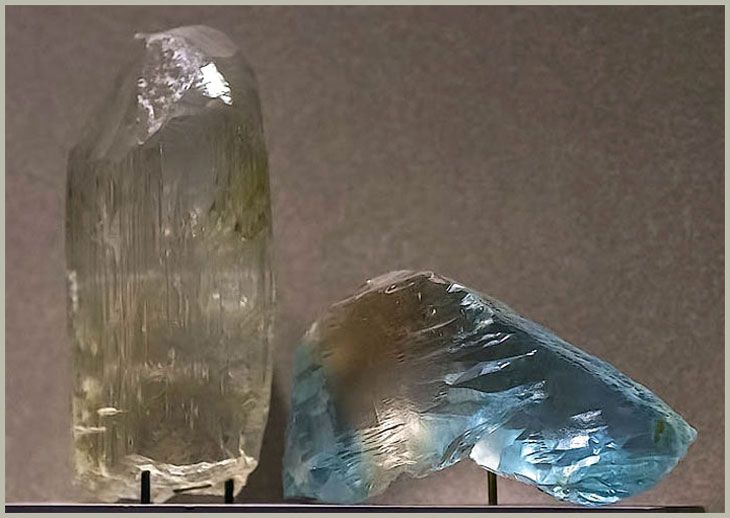 Топазы волынские: бесцветный кристалл с формами природного растворения, и двухцветный чайно-голубой спайный выколок. Национальный музей естественной истории в Вашингтоне, США