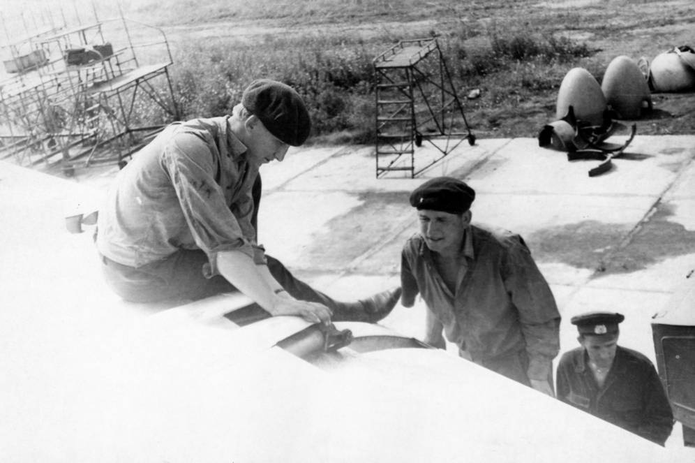Техник левого крыла наземного экипажа Ту-95КМ А. Михайленко (на фото слева) осматривает карданную головку шариковинтового подъемника закрылков перед ее подсоединением к каретке (она пока демонтирована).Авиабаза Моздок, конец 60-х гг.
